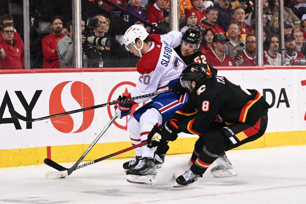 

Obranca Calgary Flames MacKenzie Weegar (52) a Christopher Tanev (8) blokujú útočníka Montrealu Canadiens Juraja Slafkovského (20). FOTO: Reuters/USA TODAY Sports/Candice Ward