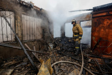 Hasič zasahuje v horiacej budove v Donecku, ktorú poškodilo ostreľovanie. FOTO: REUTERS