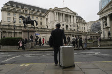 Muž stojí s kufrom pred britskou centrálnou bankou v Londýne.  FOTO: TASR/AP