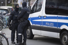 Policajti stoja pri prehľadávanom objekte počas razie voči členom krajne pravicového hnutia Reichsbürger.