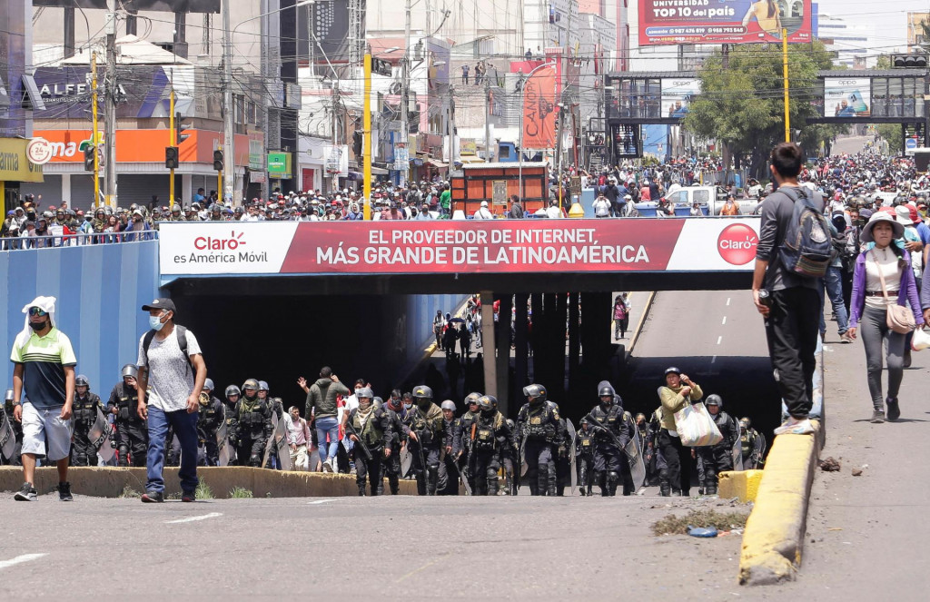 Policajti kráčajú vedľa demonštrantov, ktorí sa zúčastňujú pochodu požadujúceho rozpustenie Kongresu a usporiadanie demokratických volieb namiesto toho, aby uznali Dinu Boluarteovú za peruánsku prezidentku. FOTO: Reuters