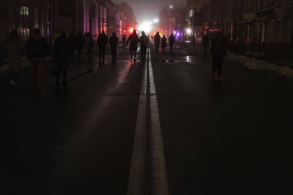 Ľudia kráčajú po tmavej ulici v centre Kyjeva počas výpadku elektriny po ruskom ostreľovaní. FOTO: TASR/AP
