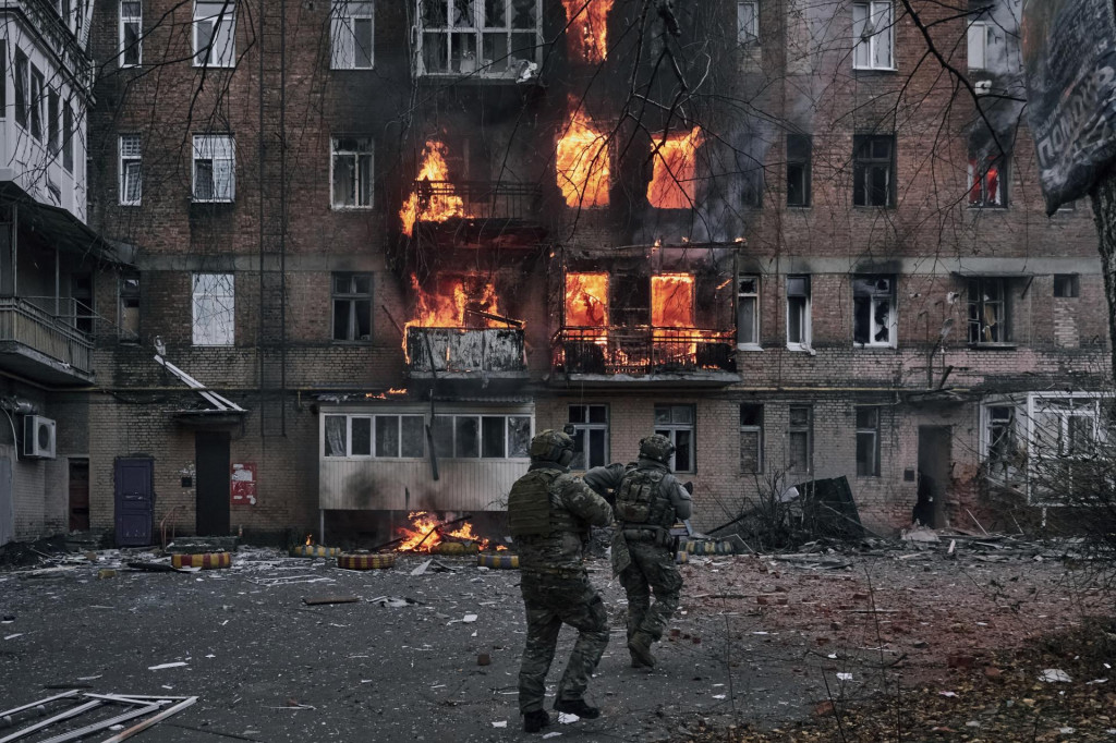 Ukrajinskí vojaci bežia na pomoc obyvateľom horiacej obytnej budovy po ruskom útoku v meste Bachmut na Donbase. FOTO: TASR/AP