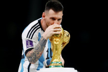 Lionel Messi symbolicky bozkáva trofej po víťazstve nad Francúzskom po finálne MS v Katare. FOTO: REUTERS