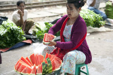 Predavačka krája melón pre zákazníkov na železničnej stanici v Rangúne. FOTO: TASR/AP