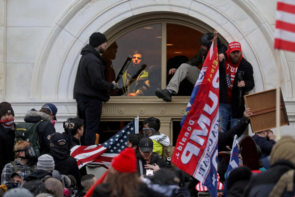 Dav priaznivcov vtedajšieho prezidenta USA Donalda Trumpa preliezol oknom, ktoré rozbili pri útoku na budovu amerického Kapitolu. FOTO: Reuters