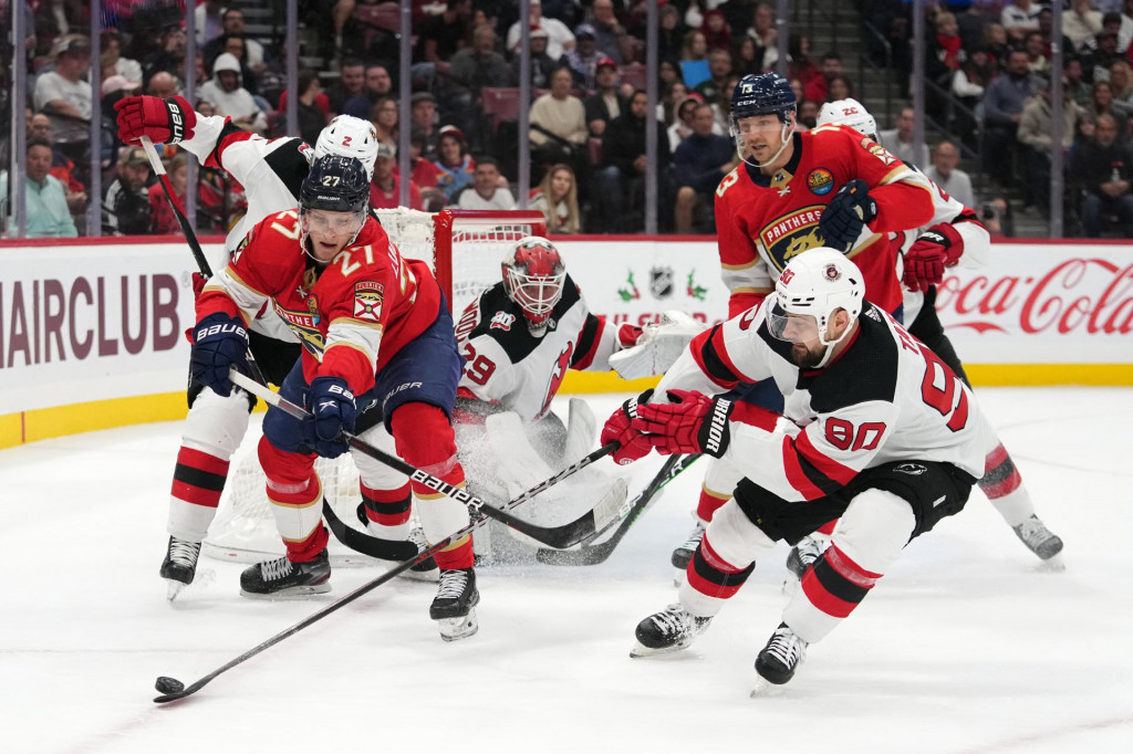 Dec 21, 2022; Sunrise, Florida, USA; New Jersey Devils left wing Tomas Tatar (90) knocks the puck away from Florida Panthers center Eetu Luostarinen (27) during the second period at FLA Live Arena. Mandatory Credit: Jasen Vinlove-USA TODAY Sports SN&Iacute;MKA: Jasen Vinlove