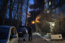 Obyvatelia sa pozerajú na horiaci projekt infraštruktúry, ktorý bol zasiahnutý počas masívneho nočného útoku ruského dronu v Kyjeve. FOTO: TASR/AP