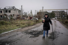 Ukrajinka kráča popri zničených budovách. Mesto Cherson Rusi pravidelne ostreľovali, pričom zámerne narušili aj elektrickú infraštruktúru. FOTO: REUTERS