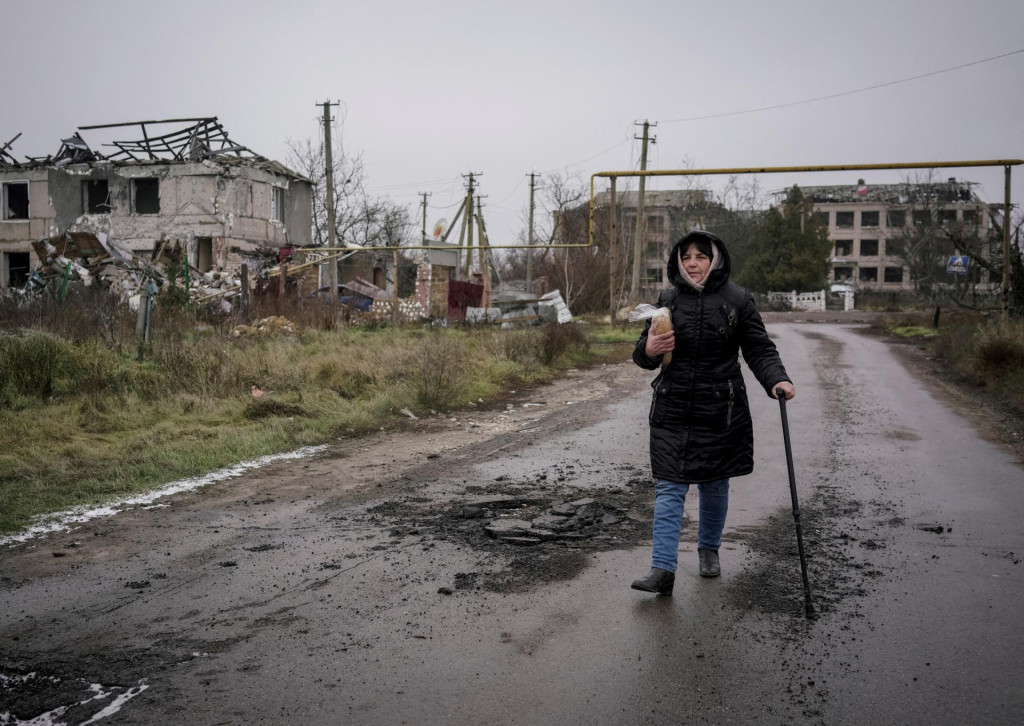 Ukrajinka kráča popri zničených budovách. Mesto Cherson Rusi pravidelne ostreľovali, pričom zámerne narušili aj elektrickú infraštruktúru. FOTO: REUTERS