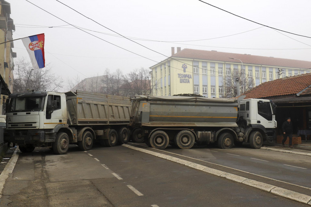 Muž kráča okolo naložených nákladných áut, ktoré blokujú cestu v meste Mitrovica na severe Kosova. FOTO: TASR/AP