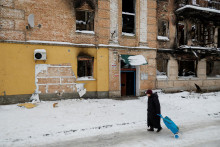 Miestna žena kráča vedľa múru obytného domu, ťažko poškodeného počas ruskej invázie, z ktorého sa skupina ľudí pokúsila ukradnúť dielo pouličného umelca Banksyho. FOTO: Reuters