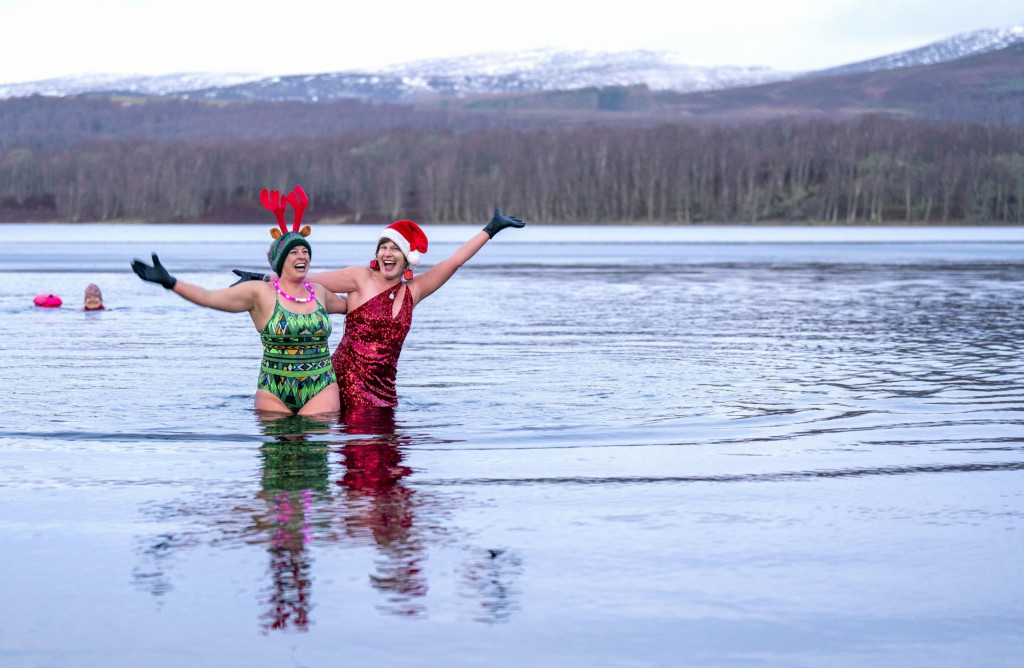 Dve ženy zo skupiny otužilcov sa kúpu počas vianočného otužovania v jazere Loch Insh v Národnom parku Cairngorms pri škótskom meste Aviemore 23. decembra 2022.