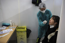 Zdravotníčka testuje cestujúcu prichádzajúcu z Číny na ochorenie COVID-19 v testovacej kabínke na letisku Charlesa de Gaulla pri Paríži. FOTO: TASR/AP