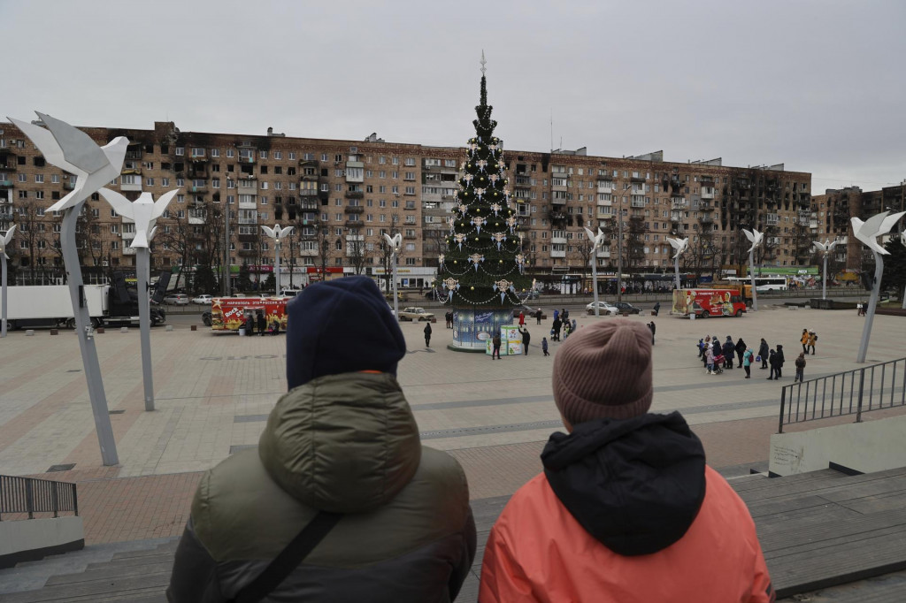 Miestni obyvatelia kráčajú okolo vianočného stromu vo východoukrajinskom meste Mariupol v Doneckej oblasti kontrolovanej Ruskom. FOTO: TASR/AP
