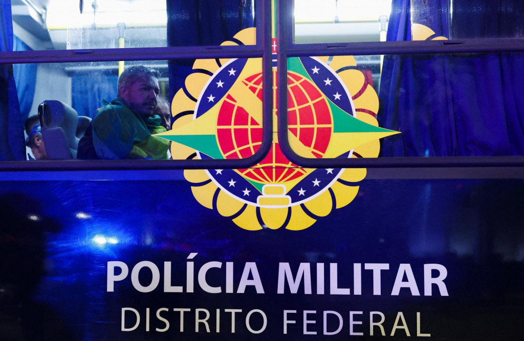 Zadržaní priaznivci bývalého brazílskeho prezidenta Jaira Bolsonara sedia v autobuse, ktorý ich odvezie na policajnú stanicu, v Brazílii, 8. januára 2023. FOTO: REUTERS
