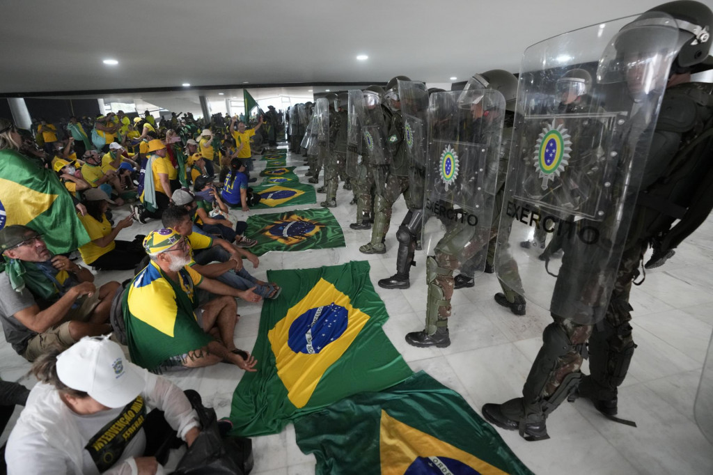 Podporovatelia bývalého brazílskeho prezidenta Jaira Bolsonara sedia pred políciou v prezidentskom paláci. Polícia v brazílskom hlavnom meste Brasília zatkla stovky osôb. FOTO: TASR/AP