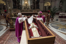 Biskupi Georg Gaenswein (vpravo) a Diego Ravelli zakrývajú tvár zosnulého emeritného pápeža Benedikta XVI. bielym hodvábnym súknom v cyprusovej rakve vystavenej v Bazilike sv. Petra vo Vatikáne. FOTO: TASR/AP