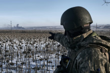 Ukrajinský vojak ukazuje na dym počas bojov medzi ukrajinskou a ruskou armádou o mesto Soledar. FOTO: TASR/AP