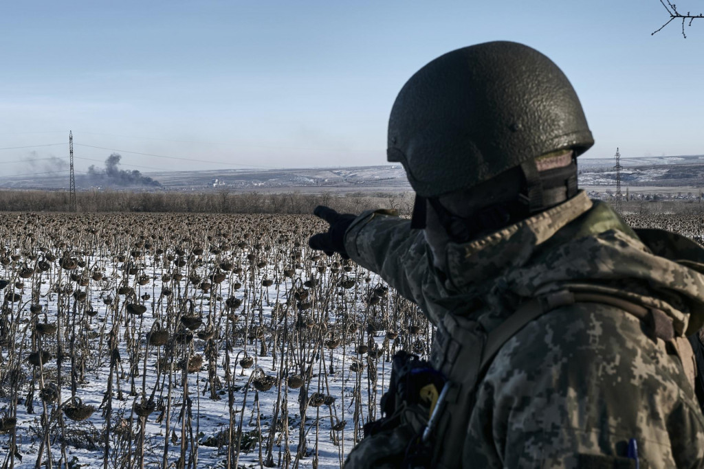 Ukrajinský vojak ukazuje na dym počas bojov medzi ukrajinskou a ruskou armádou o mesto Soledar v Doneckej oblasti na východe Ukrajiny. FOTO: TASR/AP

