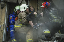 Ukrajinsk&iacute; hasiči nes&uacute; zranen&uacute; ženu z ru&iacute;n obytnej budovy v ukrajinskom meste Dnipro. FOTO: TASR/AP