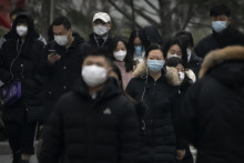 Cestujúci s rúškami a respirátormi na tvári proti šíreniu ochorenia COVID-19 kráčajú ulicami Pekingu. FOTO: TASR/AP
