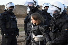 Policajti vedú švédsku klimatickú aktivistku Gretu Thunbergovú z demolačnej zóny počas protestnej akcie klimatických aktivistov. FOTO TASR/AP
