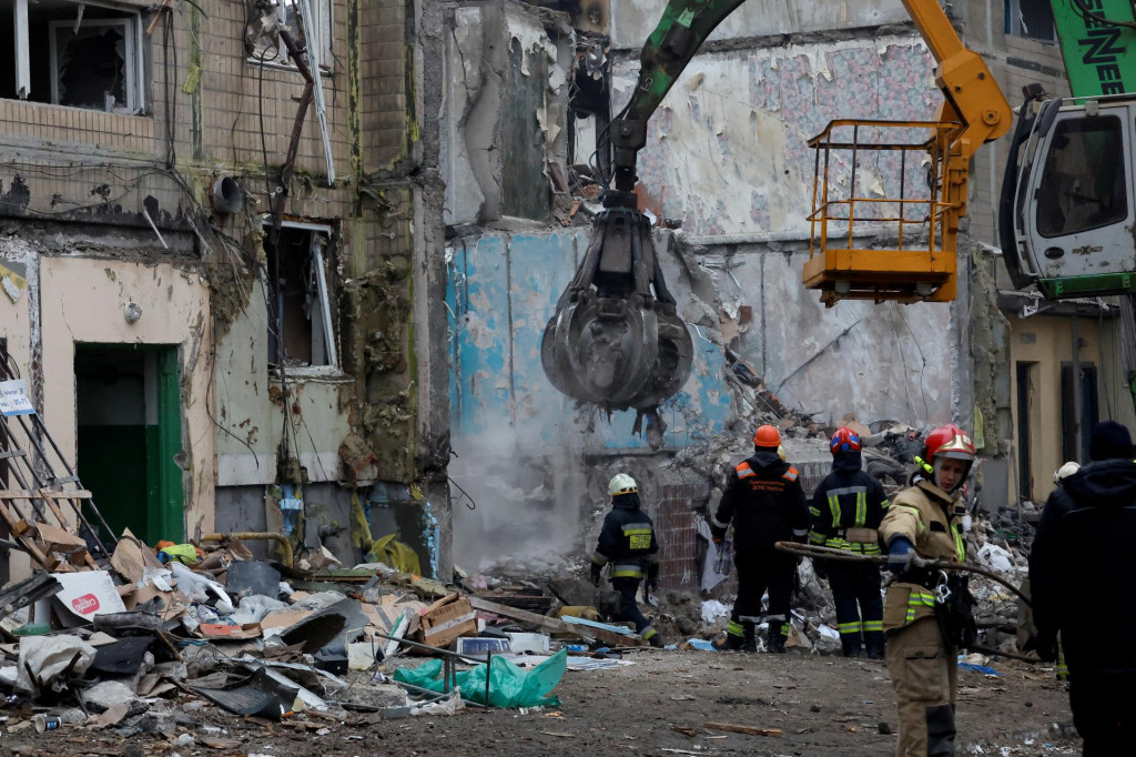 Záchranári pri práci v blízkosti budovy v Dnipre, ktorá následkom raketového útoku utrpela rozsiahle poškodenie. FOTO: Reuters