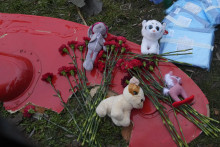 Kvety a plyšové hračky sú položené na fragment vrtuľníka, ktorý sa zrútil pri budove materskej školy a bytovky v meste Brovary pri Kyjeve. FOTO: TASR/AP