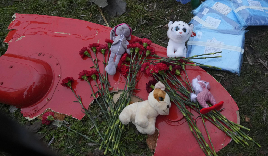 Kvety a plyšové hračky sú položené na fragment vrtuľníka, ktorý sa zrútil pri budove materskej školy a bytovky v meste Brovary pri Kyjeve. FOTO: TASR/AP