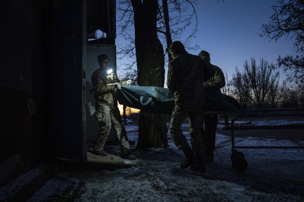 Ukrajinskí vojenskí lekári odnášajú telo zabitého ukrajinského vojaka do márnice v Doneckej oblasti na východe Ukrajiny. FOTO: TASR/AP