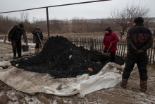 Ľudia naberajú uhlie lopatami, aby si vykúrili svoje domovy. Donecká oblasť, Ukrajina, 15. januára 2023. FOTO: REUTERS