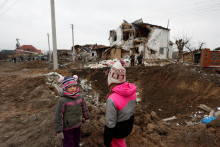 Deti stoja na mieste, ktoré zničili ruské letecké útoky na Ukrajine. FOTO: Reuters