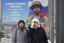 Ženy v Petrohrade pred bilbordom s portrétom ruského vojaka oceneného za akciu vo vojne na Ukrajine. FOTO: TASR/AP
