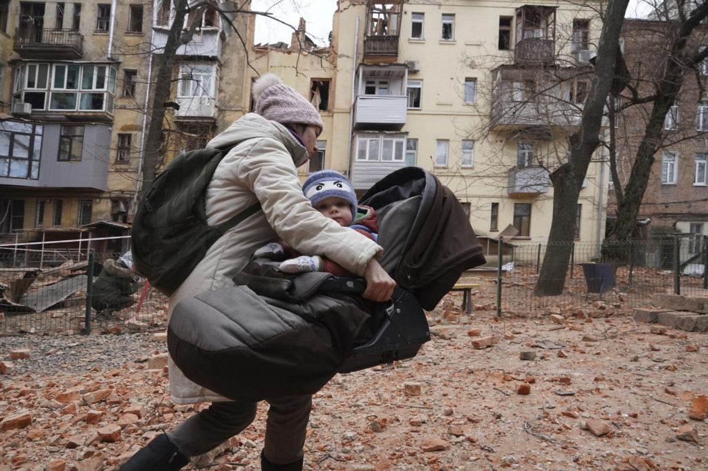 Žena nesie svoje dieťa počas evakuácie z obytnej budovy, ktorú zasiahla ruská raketa. FOTO: TASR/AP

