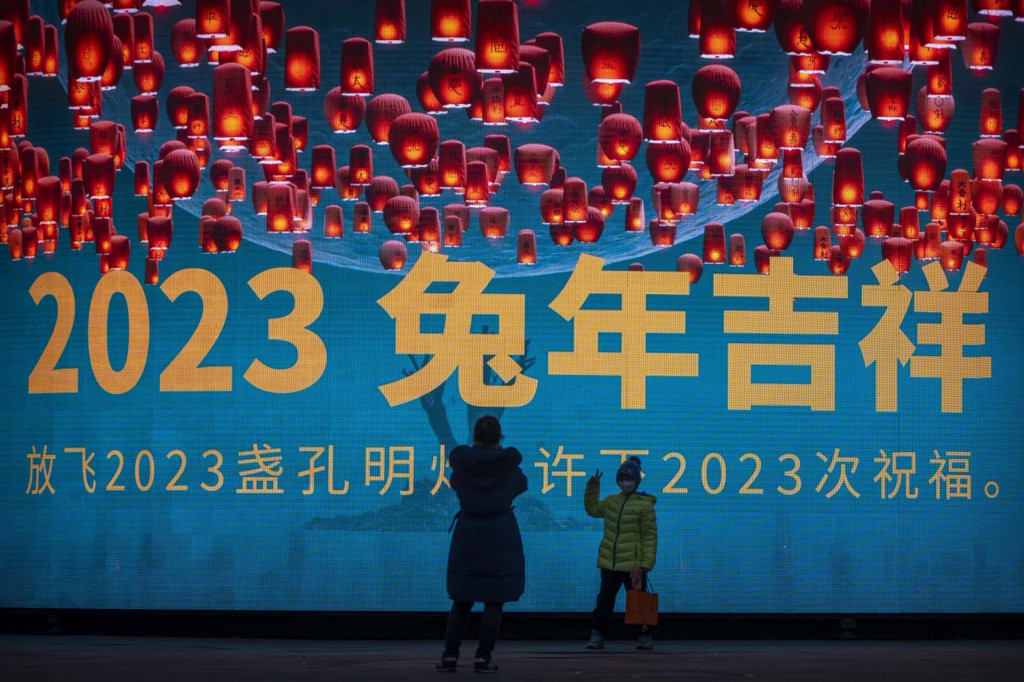 Na snímke chlapec s ochranným rúškom pózuje pred veľkou obrazovkou pri príležitosti osláv čínskeho lunárneho Nového roka v Pekingu. FOTO TASR/AP