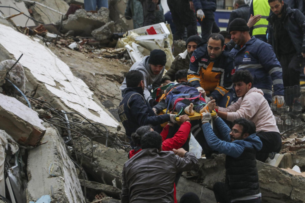 Ľudia a záchranári vynášajú preživšiu osobu, ktorú vytiahli z trosiek budovy po silnom zemetrasení v tureckom meste Adana. FOTO: TASR/AP