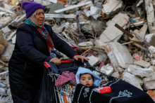Žena v meste Antakya zasiahnutom zemetrasením vezie dieťa v nákupnom vozíku. FOTO: Reuters