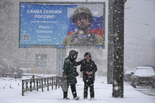 Žena sa rozpráva s chlapcom pri bilborde s portrétom ruského vojaka Ivana Kočkina a nápisom Sláva hrdinom Ruska v Petrohrade v piatok 10. februára 2023. FOTO: TASR/AP