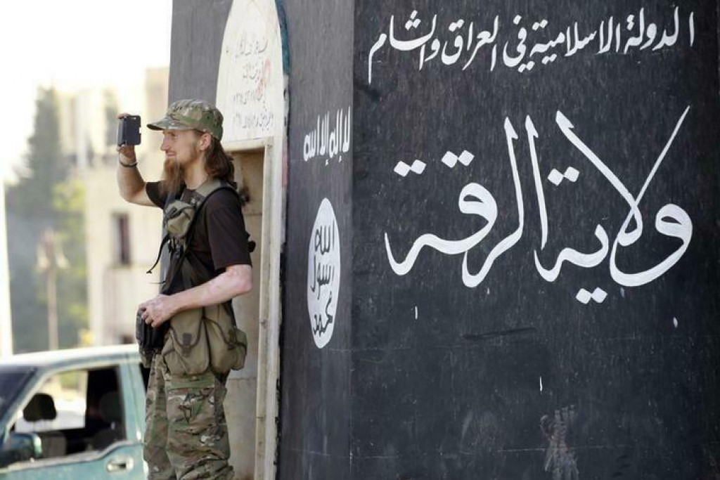 Militantný islamistický bojovník používa mobil na natáčanie svojich spolubojovníkov, ako sa zúčastňujú vojenskej prehliadky v uliciach severnej sýrskej provincie Rakka 30. júna 2014. FOTO: REUTERS SNÍMKA: Reuters