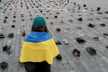 Žena sa pozerá na topánky symbolizujúce vojnové zločiny spáchané na ukrajinských civilistoch pri príležitosti ročného výročia ruskej invázie na Ukrajinu v Prahe, Česká republika. FOTO: REUTERS