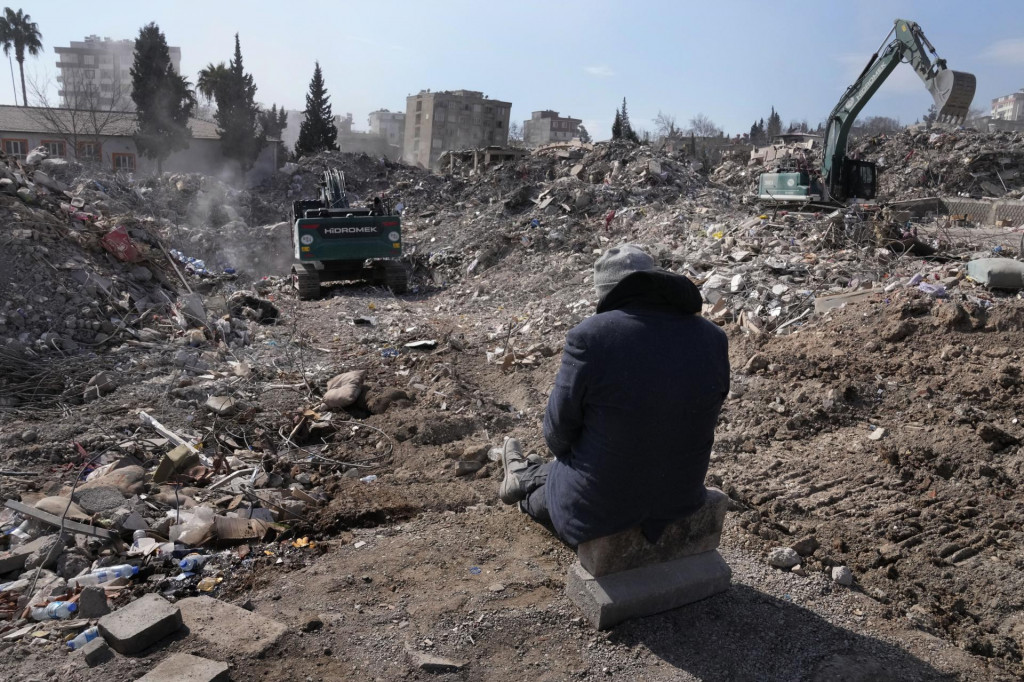 Muž sleduje prácu bágrov pri prehľadávaní trosiek zničených budov po ničivom zemetrasení v meste Kahramanmaraš na juhovýchode Turecka. FOTO: TASR/AP