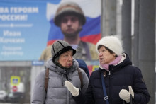 Ženy sa rozprávajú pri kráčaní okolo bilbordu s portrétom ruského vojaka oceneného za akciu vo vojne na Ukrajine, na ulici v Petrohrade 31. januára 2023. FOTO: TASR/AP