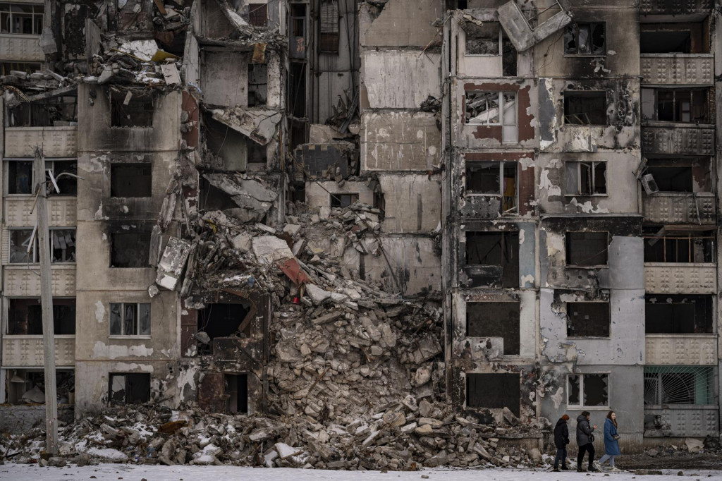 Ženy kráčajú okolo zničenej obytnej budovy po ruskom ostreľovaní v štvrti Saltivka v Charkove. FOTO: TASR/AP
