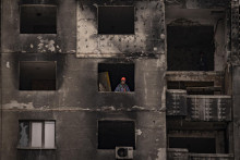 Robotník stojí v okne zničenej obytnej budovy, ktorú robotníci opravujú po ruskom ostreľovaní v štvrti Saltivka v Charkove. FOTO: TASR/AP