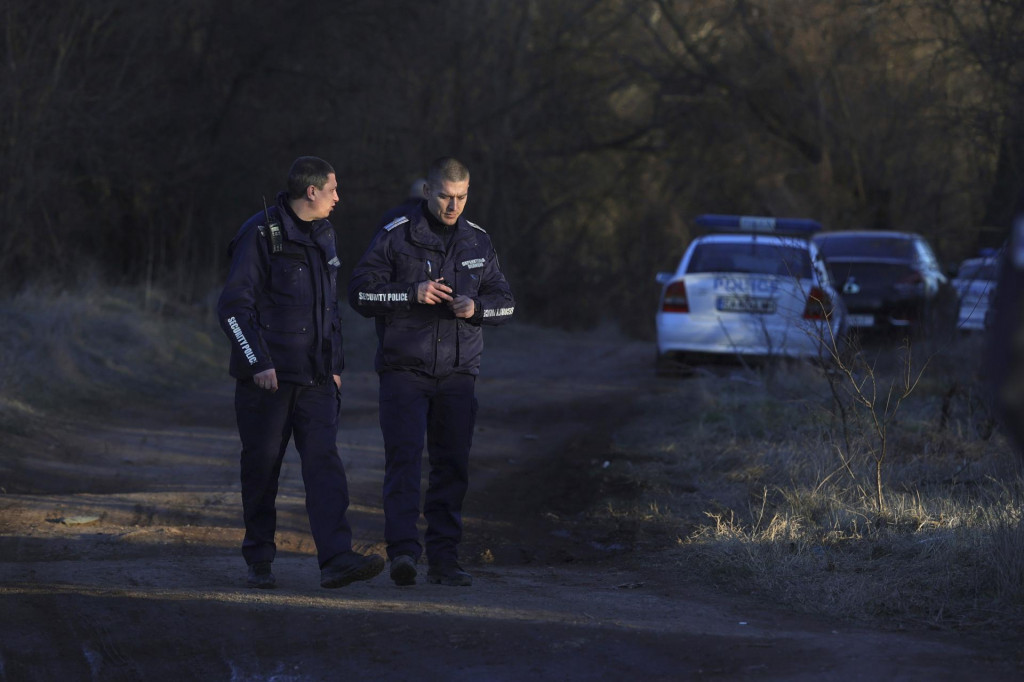 Policajti hliadkujú na mieste, kde našli opustené nákladné auto s mŕtvymi telami 18 migrantov v bulharskej denine Lokorsko, neďaleko Sofie. FOTO: TASR/AP