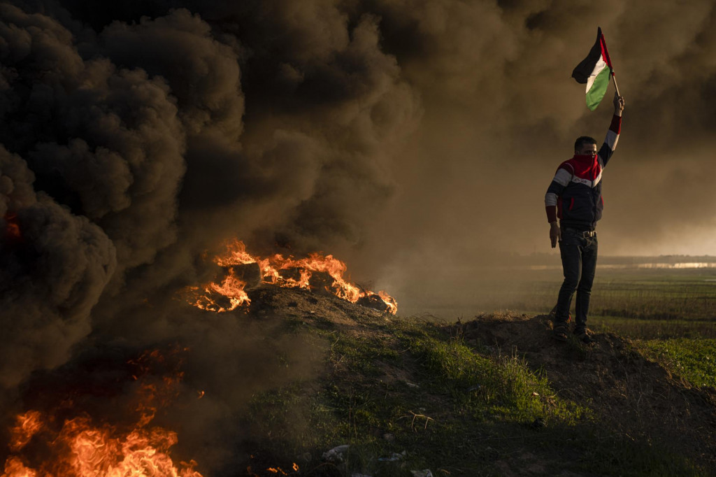 Palestínčania pália pneumatiky a mávajú národnou vlajkou počas protestu proti izraelskej vojenskej razii. FOTO: TASR/AP