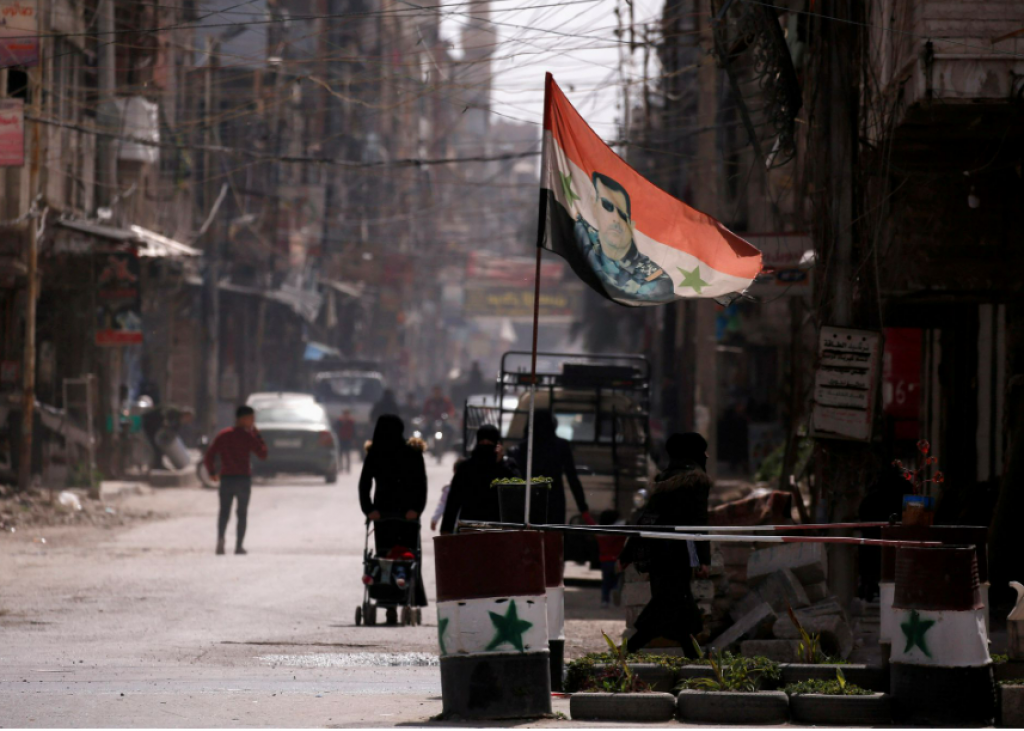 Štátna vlajka zobrazujúca obraz sýrskeho prezidenta Bašára al-Asada na kontrolnom stanovišti v Dúme na východnom predmestí Damasku v Sýrii. FOTO: REUTERS
