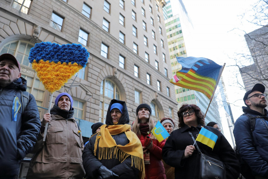 Ľudia sa zúčastňujú na ceremónii vztyčovania ukrajinskej vlajky v Bowling Green, aby si pripomenuli jeden rok od ruskej invázie na Ukrajinu v New Yorku. FOTO: Reuters