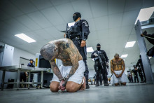 Podľa salvádorského prezidenta Nayiba Bukeleho väzenskí dozorcovia strážia členov gangu pri ich príchode po tom, ako bolo 2000 členov gangu premiestnených do väzenského centra pre terorizmus. FOTO: Reuters